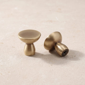 Antique brass low-profile cabinet knobs on warm limestone