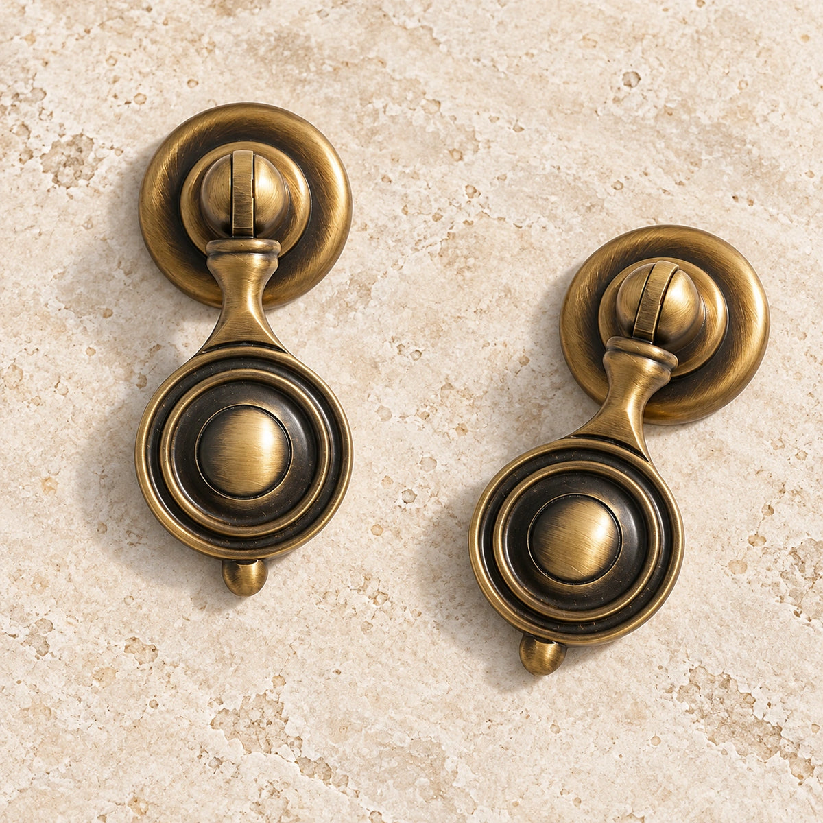 Antique brass medallion drop cabinet pulls arranged on pale limestone