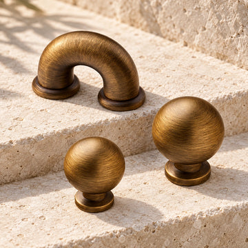 Antique brass mini arch cabinet pull with 25 and 30 mm ball knobs on limestone