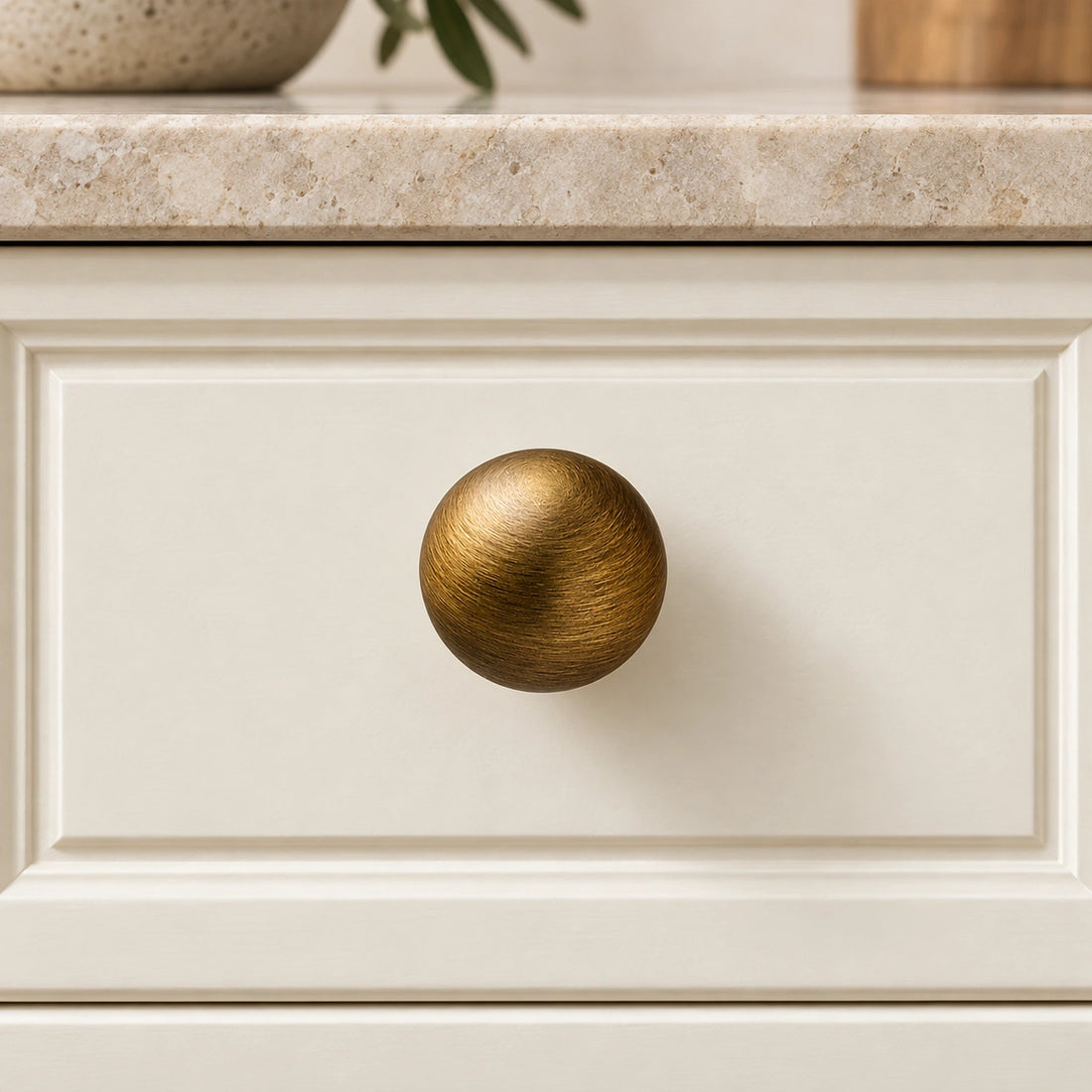 Antique brass mini arch cabinet pull with 25 and 30 mm ball knobs on limestone