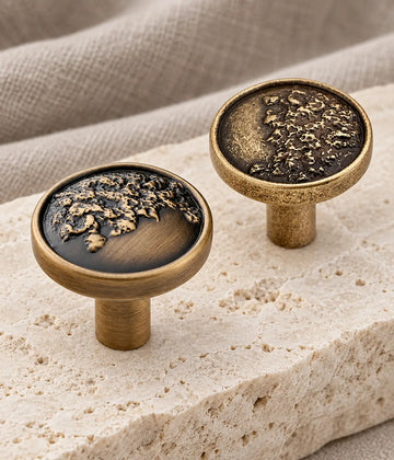 Antique brass organic relief cabinet knobs with brushed and textured rim options on limestone