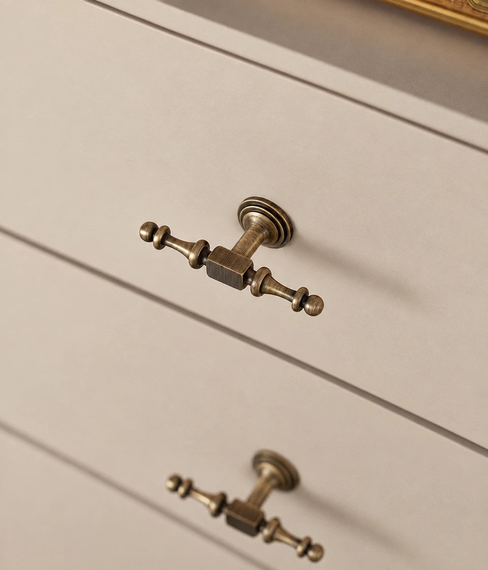 Ornate antique brass T-knobs installed on cream drawers