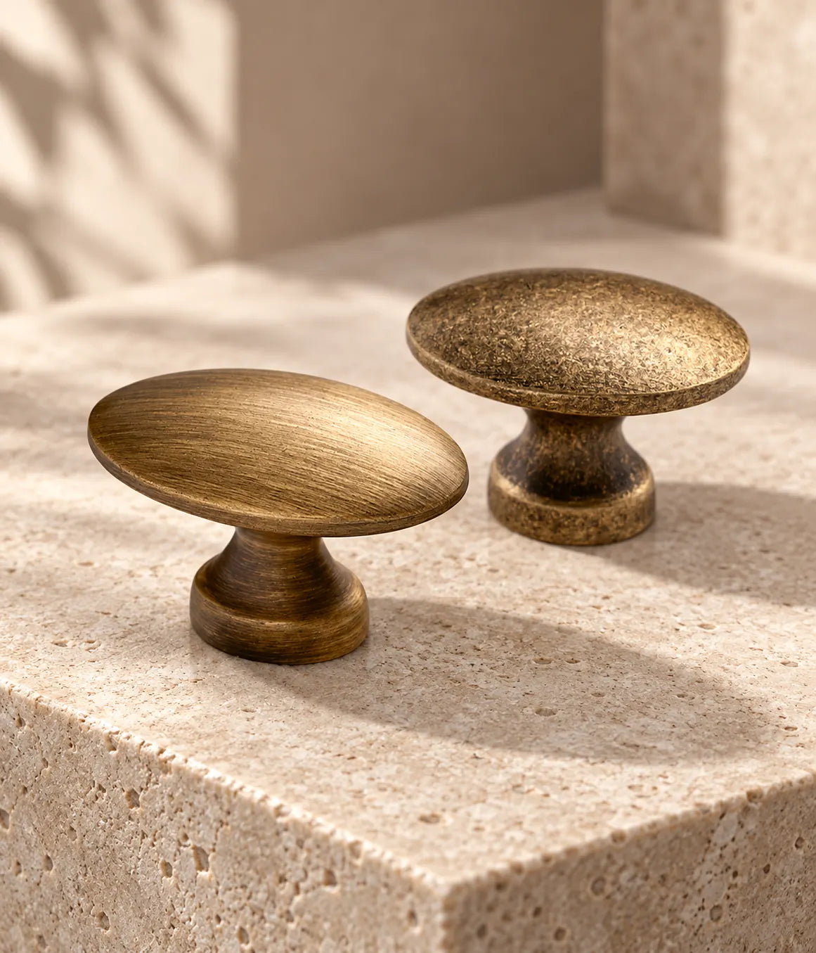 Smooth and distressed antique brass oval cabinet knobs on warm limestone