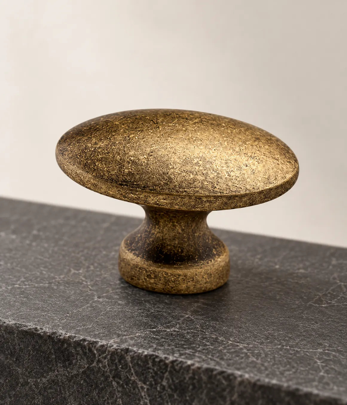 Distressed antique brass oval cabinet knob with mottled patina
