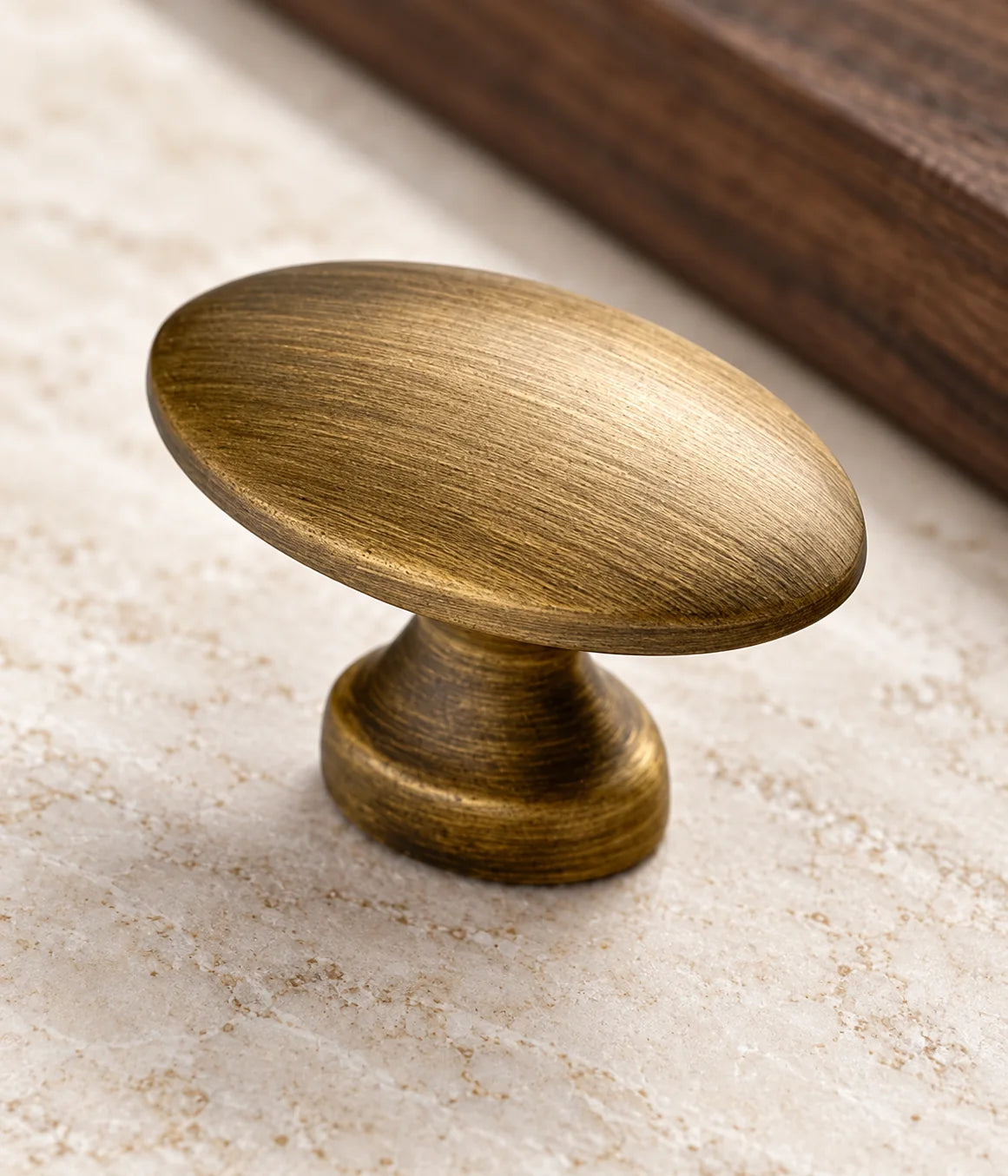 Smooth brushed antique brass oval knob with a flared pedestal base