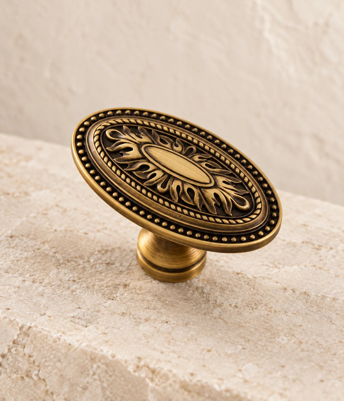 Close view of the oval medallion and decorative leaf relief on an antique brass cabinet knob