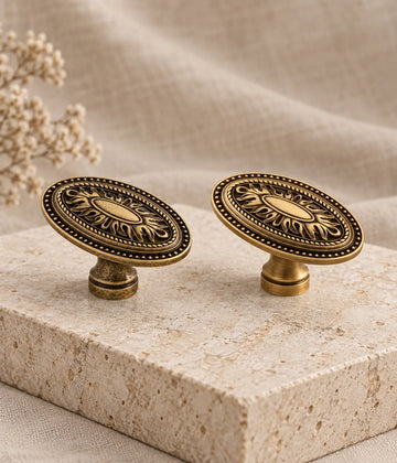 Antique brass oval medallion cabinet knobs in aged patina and brushed styles on limestone