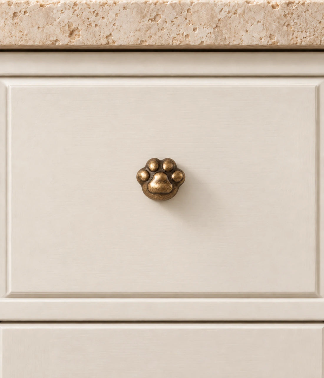Antique brass paw cabinet knob shown in two views on limestone