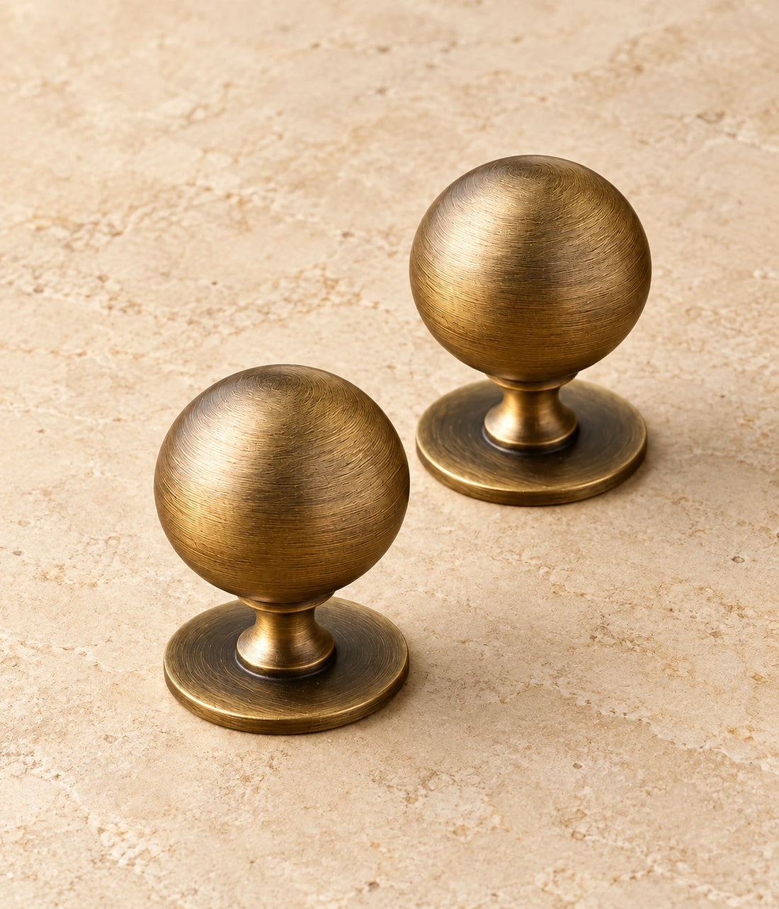 Antique Brass Pedestal Ball Cabinet Knob on warm limestone