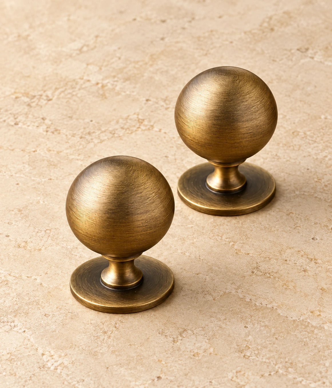 Antique Brass Pedestal Ball Cabinet Knob on warm limestone