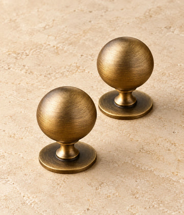 Antique Brass Pedestal Ball Cabinet Knob on warm limestone