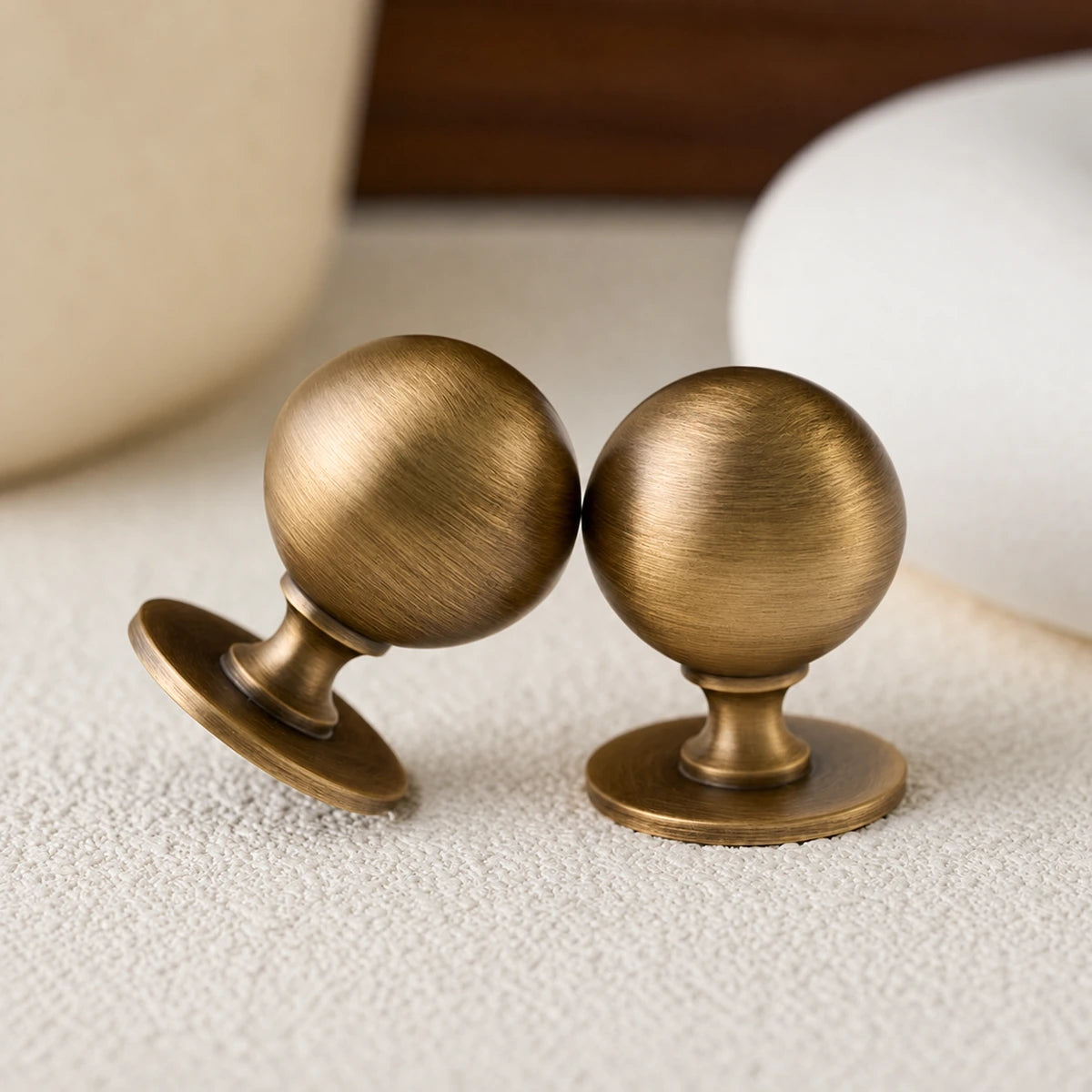 Close view of spherical brushed brass knobs and curved pedestal bases