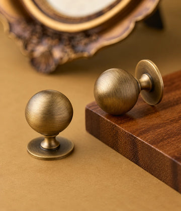 Antique brass pedestal ball knobs arranged beside a wood block