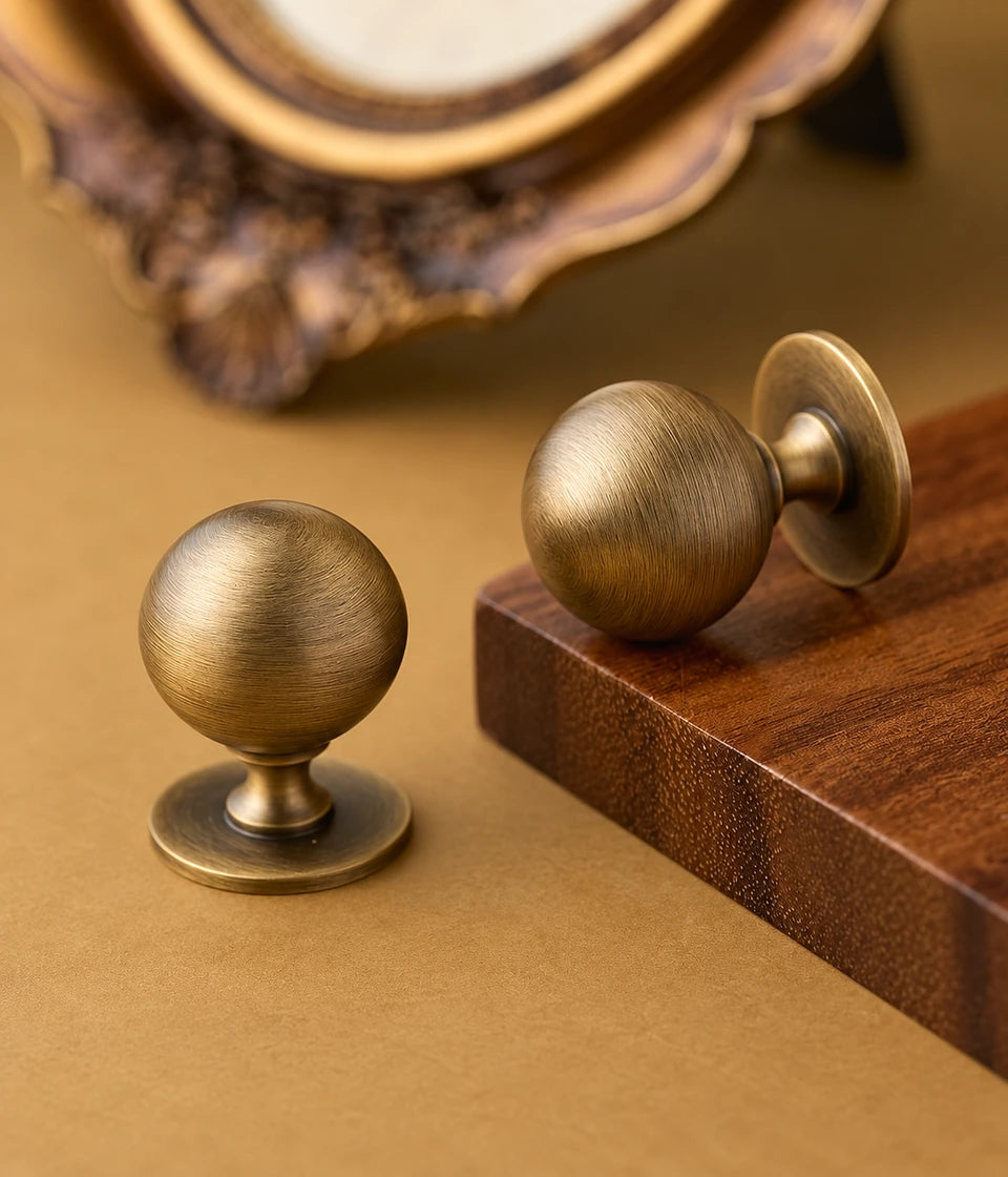 Antique brass pedestal ball knobs arranged beside a wood block