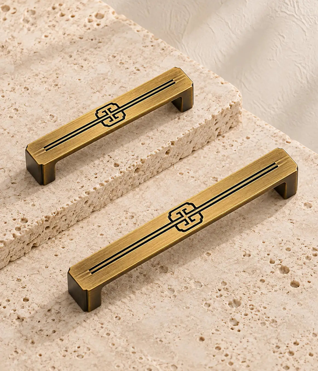 Antique brass quatrefoil scroll cabinet pulls in two sizes on pale travertine