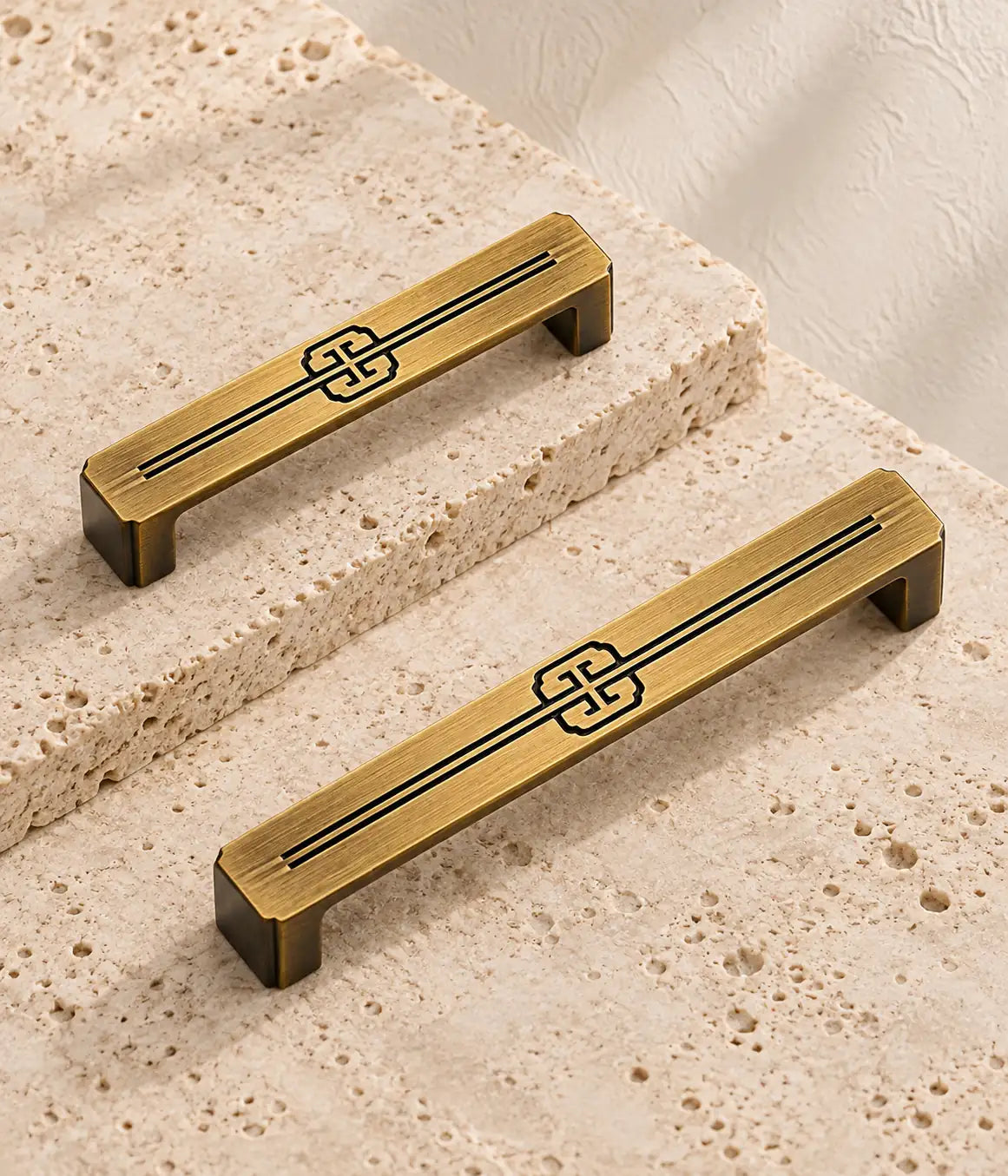 Antique brass quatrefoil scroll cabinet pulls in two sizes on pale travertine