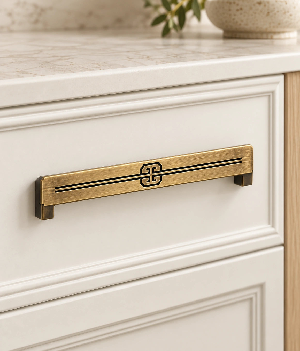 Antique brass scroll cabinet pull installed on an ivory drawer front