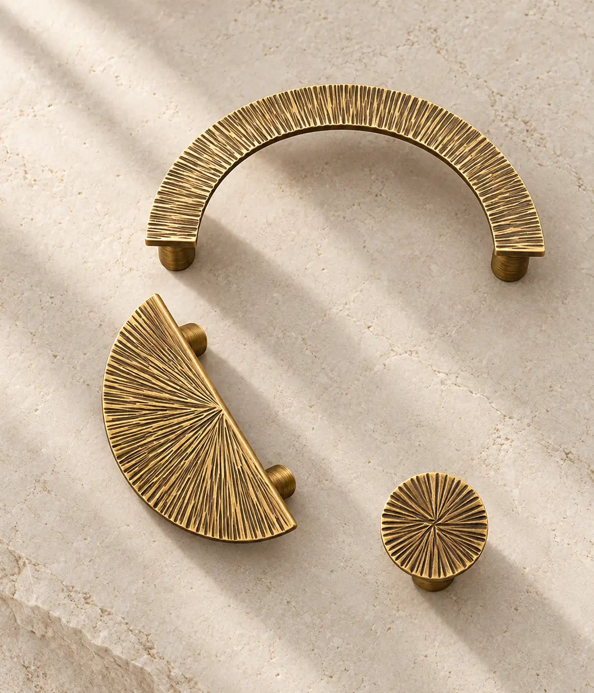 Antique brass radial half-moon pull, open arch pull and round knob on limestone