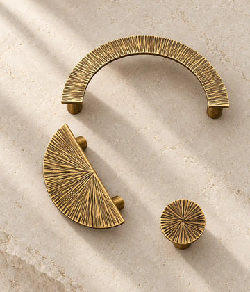 Antique brass radial half-moon pull, open arch pull and round knob on limestone