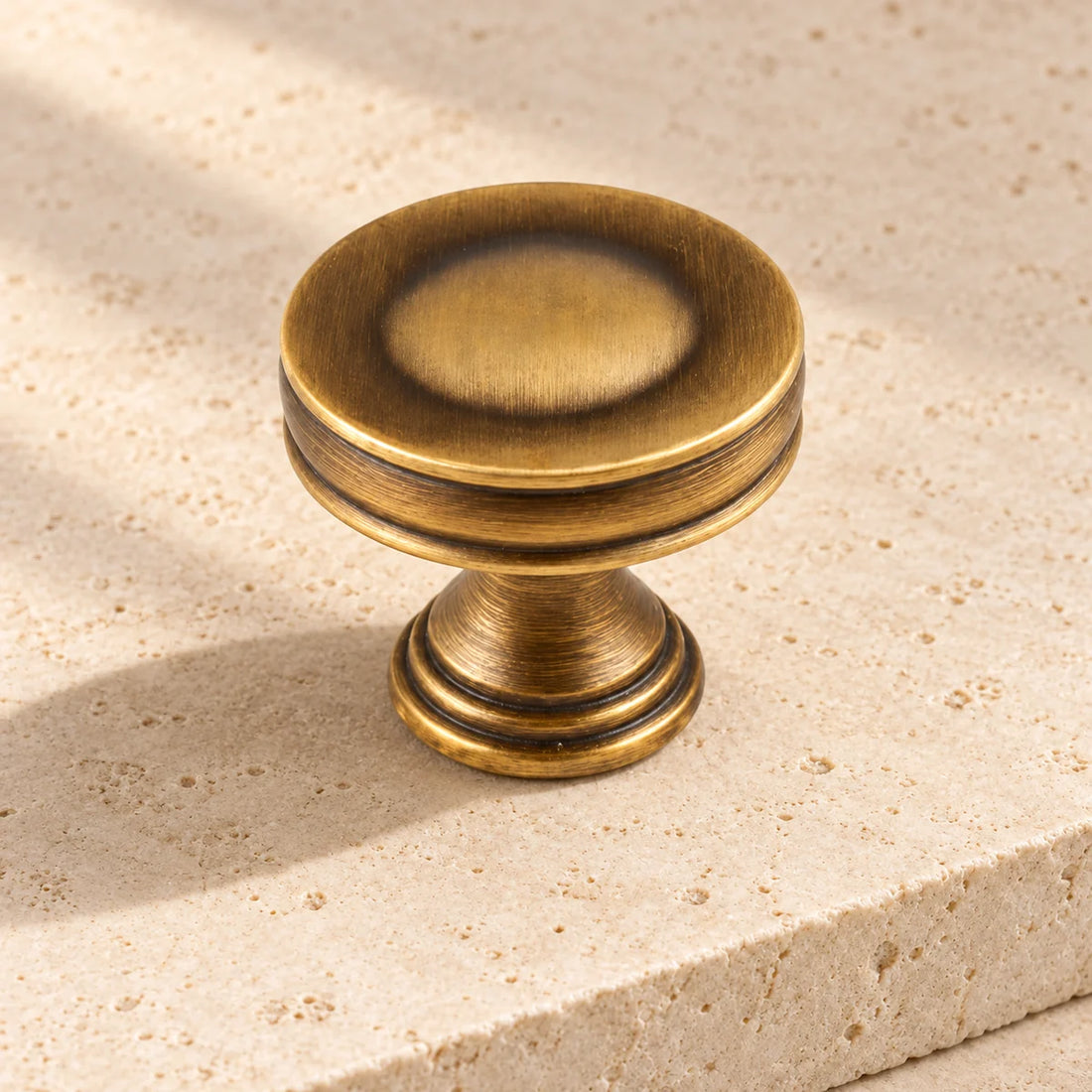 antique brass recessed ring cabinet knob on pale limestone.