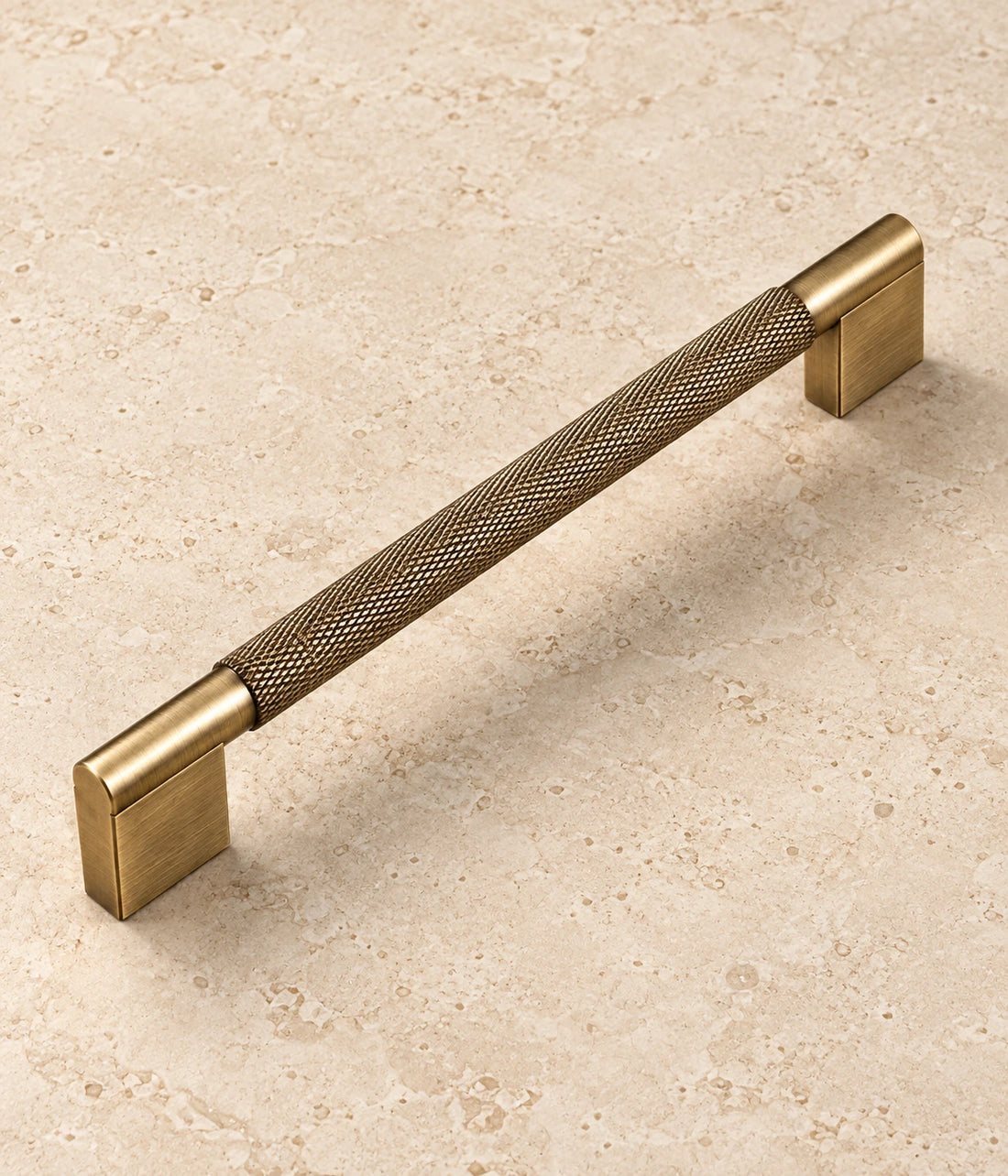Antique Brass Rectangular-Base Knurled Cabinet Pulls on warm ivory limestone