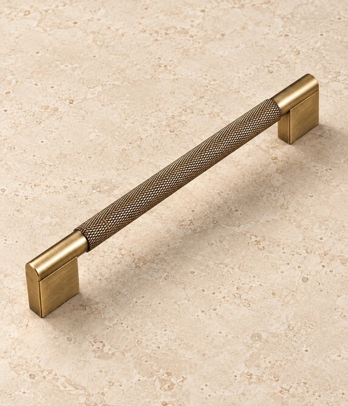 Antique Brass Rectangular-Base Knurled Cabinet Pulls on warm ivory limestone