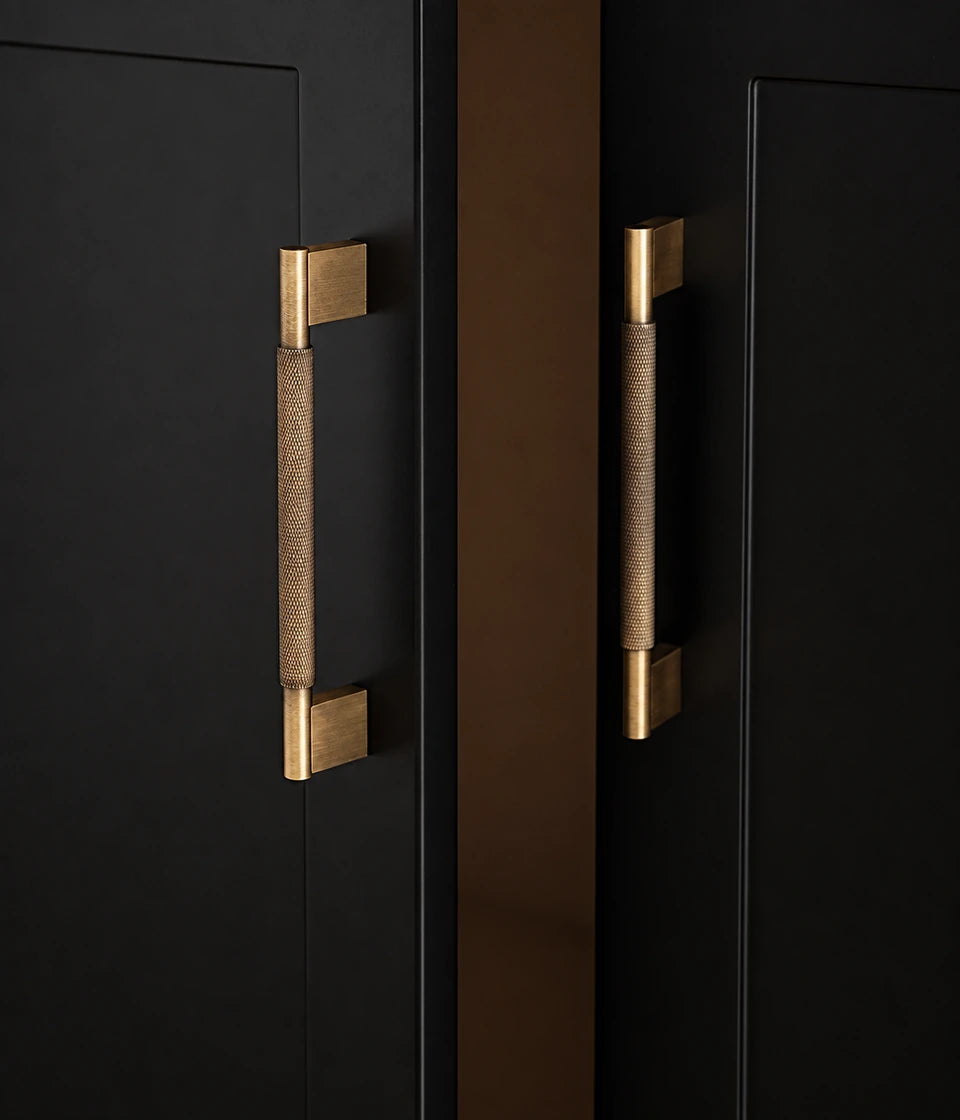 Antique brass knurled cabinet pulls with rectangular bases installed vertically on black doors