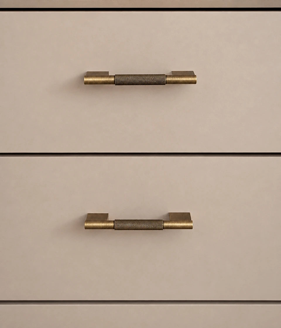 Short knurled antique brass handles mounted horizontally on cream drawers