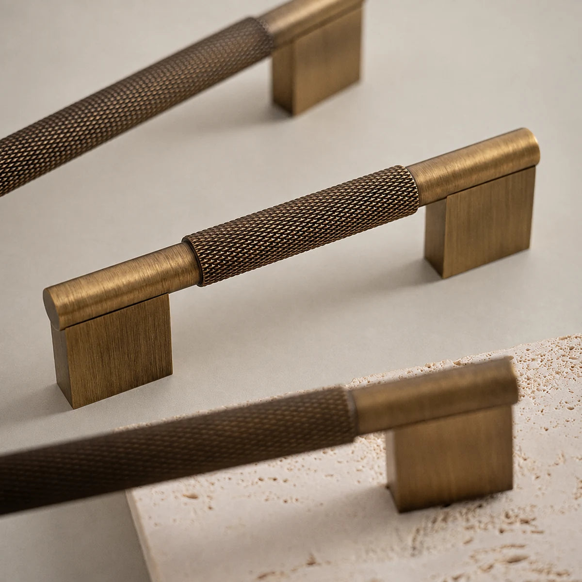 Close-up of diamond-knurled grips and flat rectangular brass bases on a cream surface