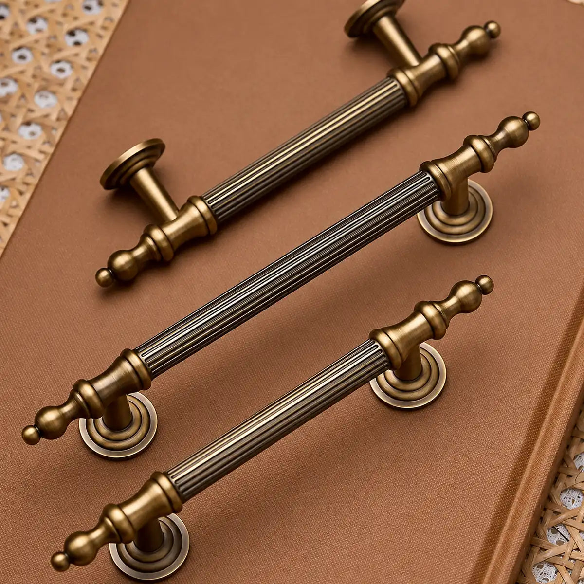 Antique brass reeded finial cabinet pulls arranged on woven fabric