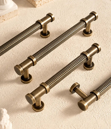Antique brass reeded cabinet pulls arranged on pale stone