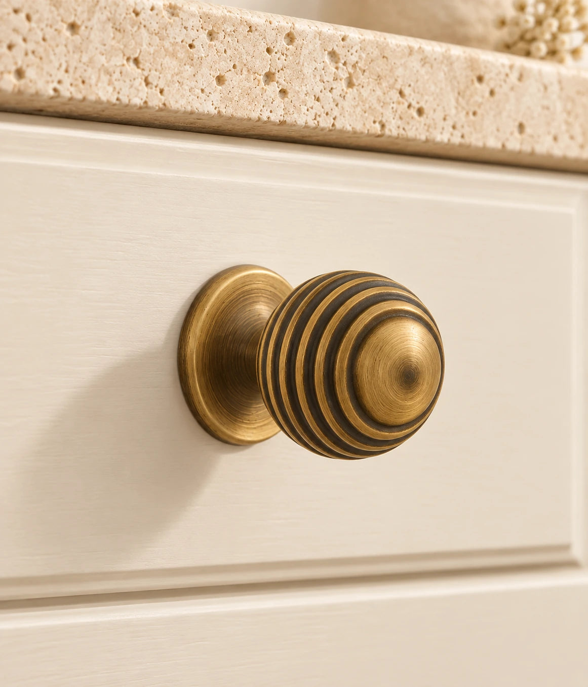 Antique Brass Ribbed Ball Cabinet Knobs installed on ivory cabinetry
