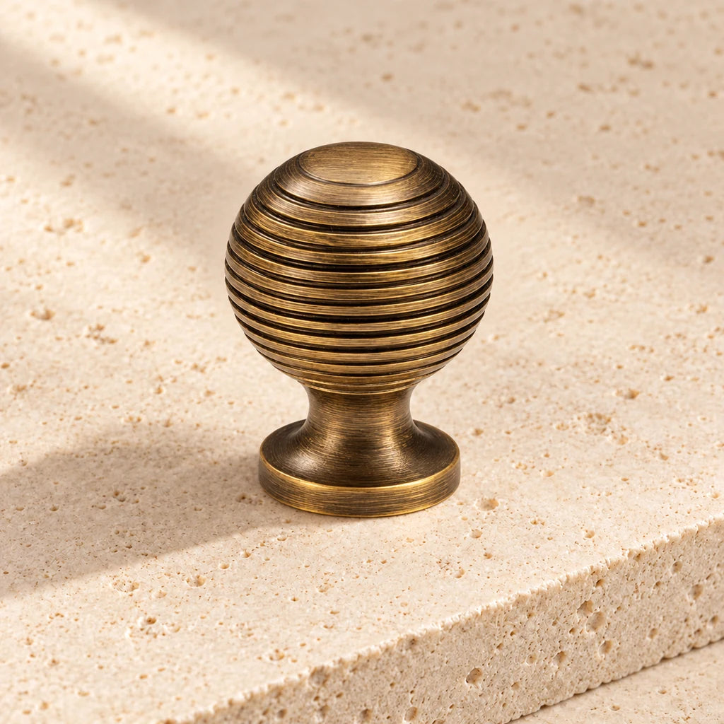antique brass ribbed ball knob on pale limestone.
