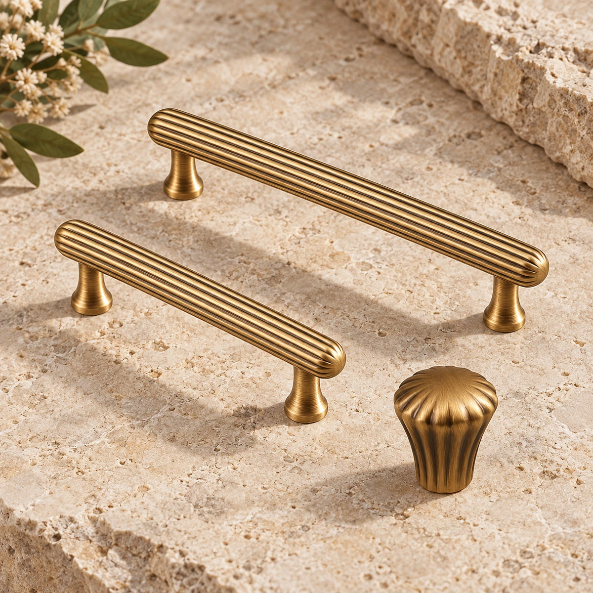 Antique brass ribbed cabinet pulls and fluted knob arranged on limestone