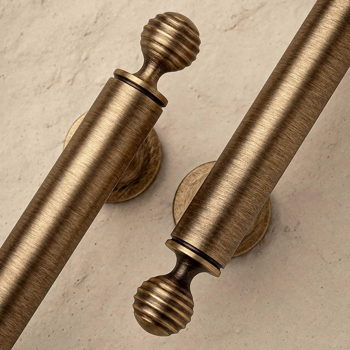 Close-up of ribbed ball finials and brushed cylindrical cabinet pull grips on pale stone