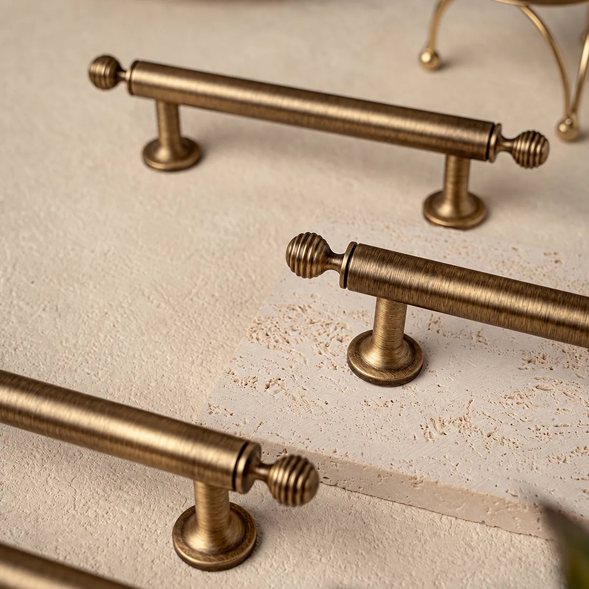 Antique brass bar pulls with ribbed ball finials arranged on pale stone