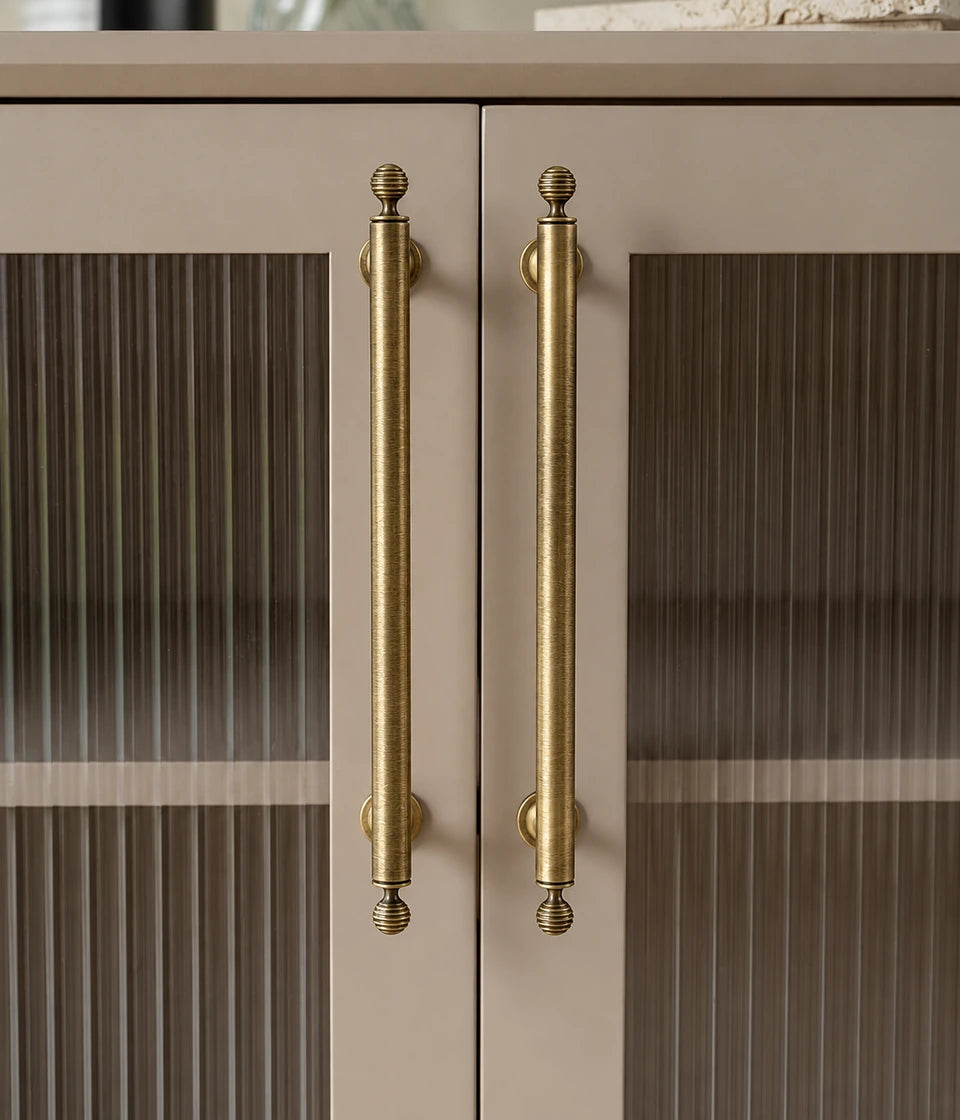 Antique brass cabinet pulls with ribbed ball finials installed on cream ribbed-glass cabinet doors