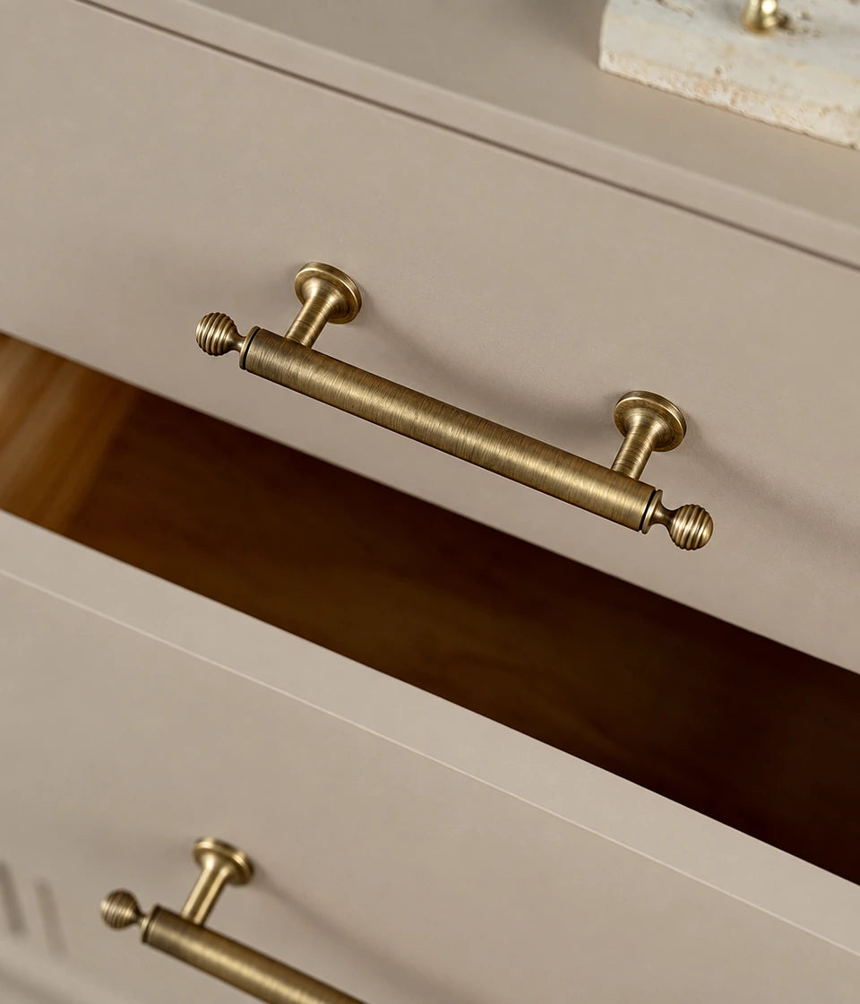 Ribbed-finial brass cabinet pull on an open cream drawer