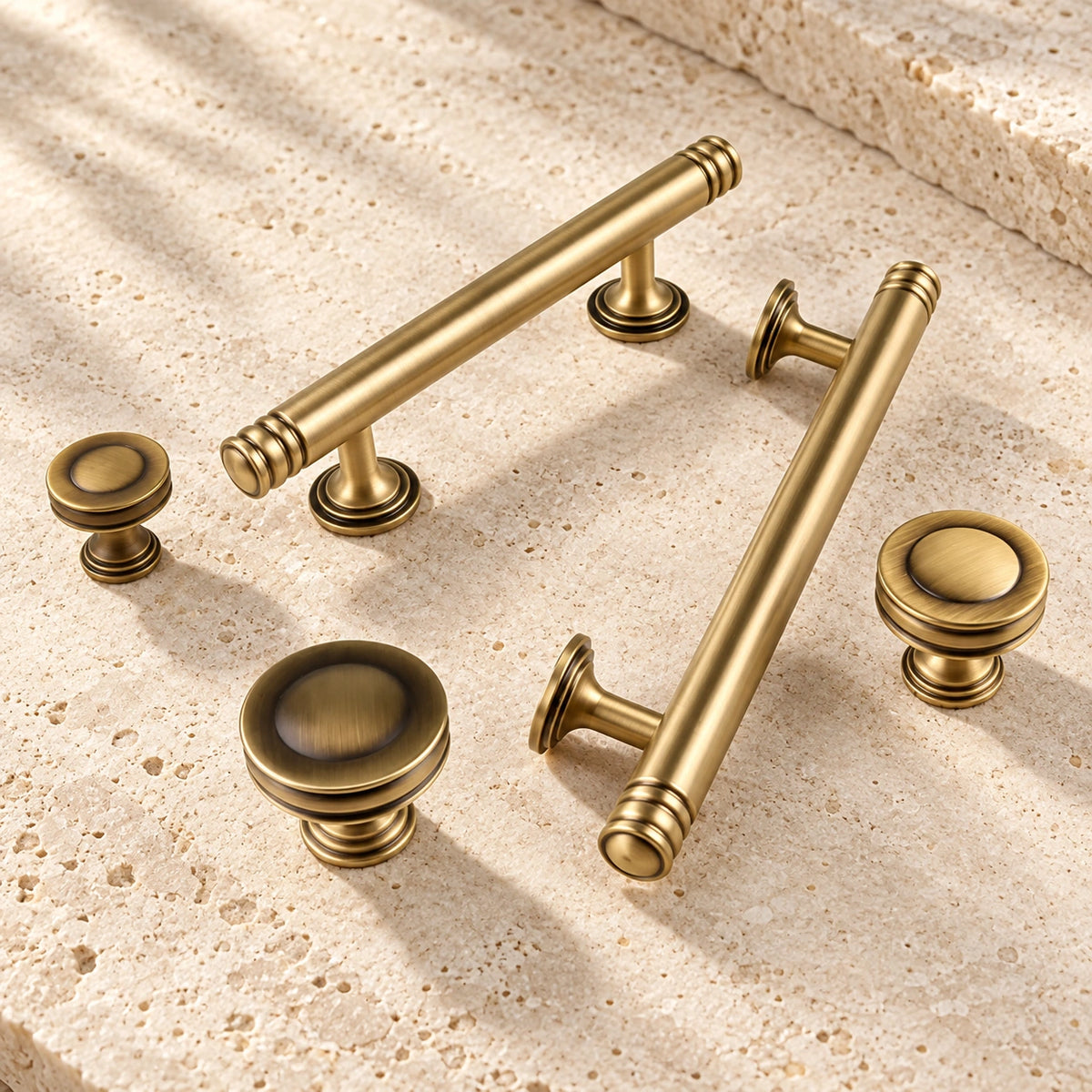 Antique brass ring-cap cabinet pulls and recessed knobs arranged on limestone