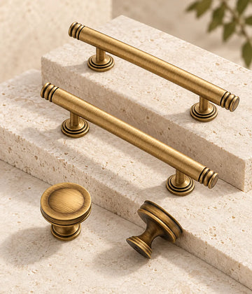 Antique brass ring-end cabinet pulls and dished knobs arranged on limestone blocks