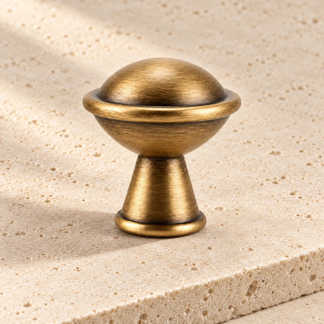antique brass ringed ball cabinet knob on pale limestone.