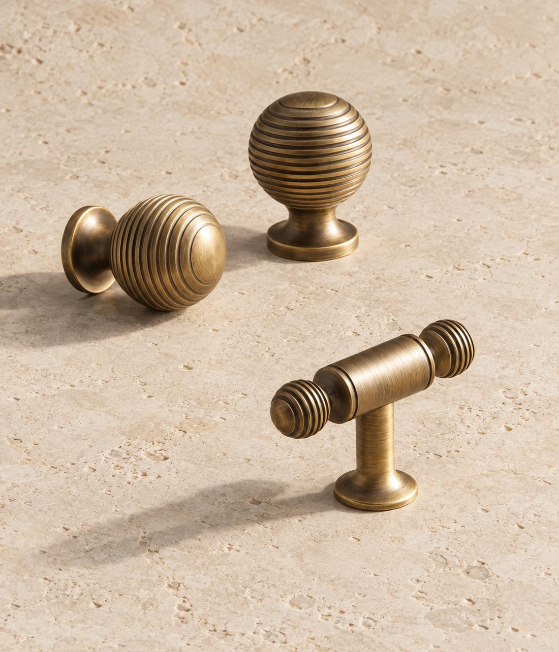 Antique Brass Ringed Ball Cabinet Pulls & Knobs arranged on warm limestone