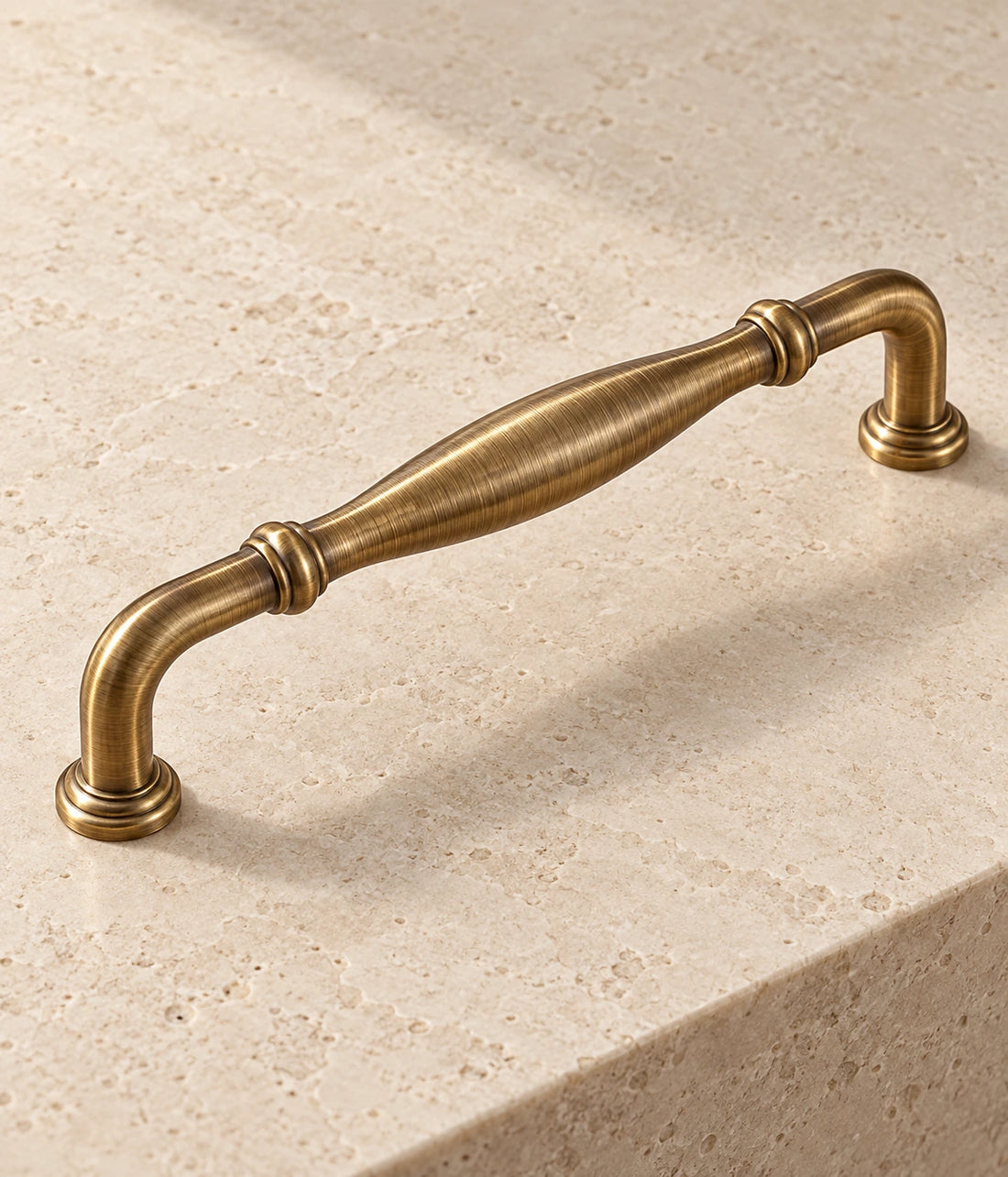 Antique Brass Ringed Bow & Pendant Cabinet Pulls on warm limestone
