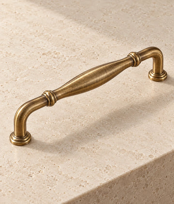 Antique Brass Ringed Bow & Pendant Cabinet Pulls on warm limestone