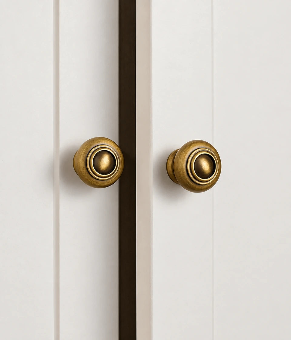 Antique brass ringed dome knobs installed on white cabinet doors