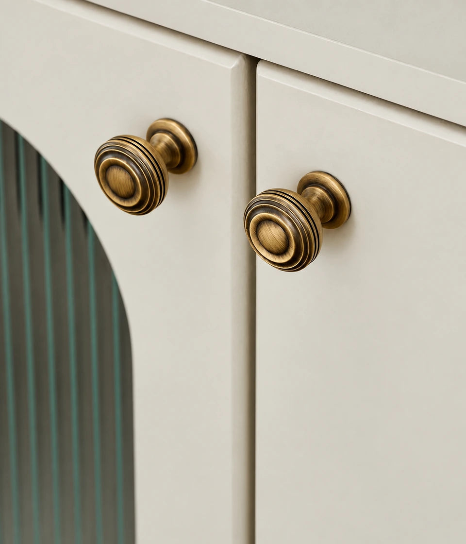 Ringed pedestal cabinet knobs installed on a cream cabinet