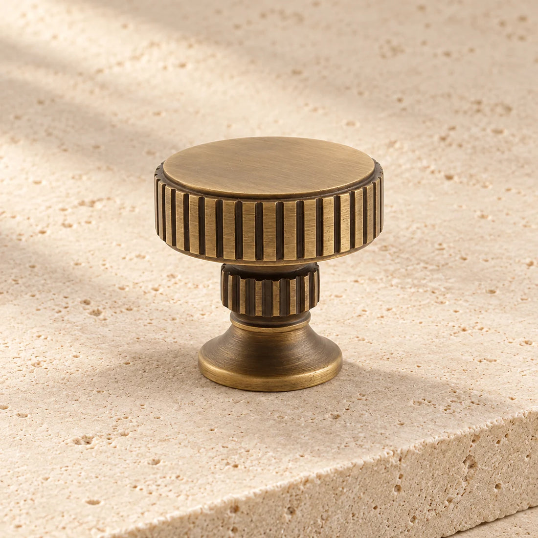 antique brass ringed round cabinet knob on pale limestone.