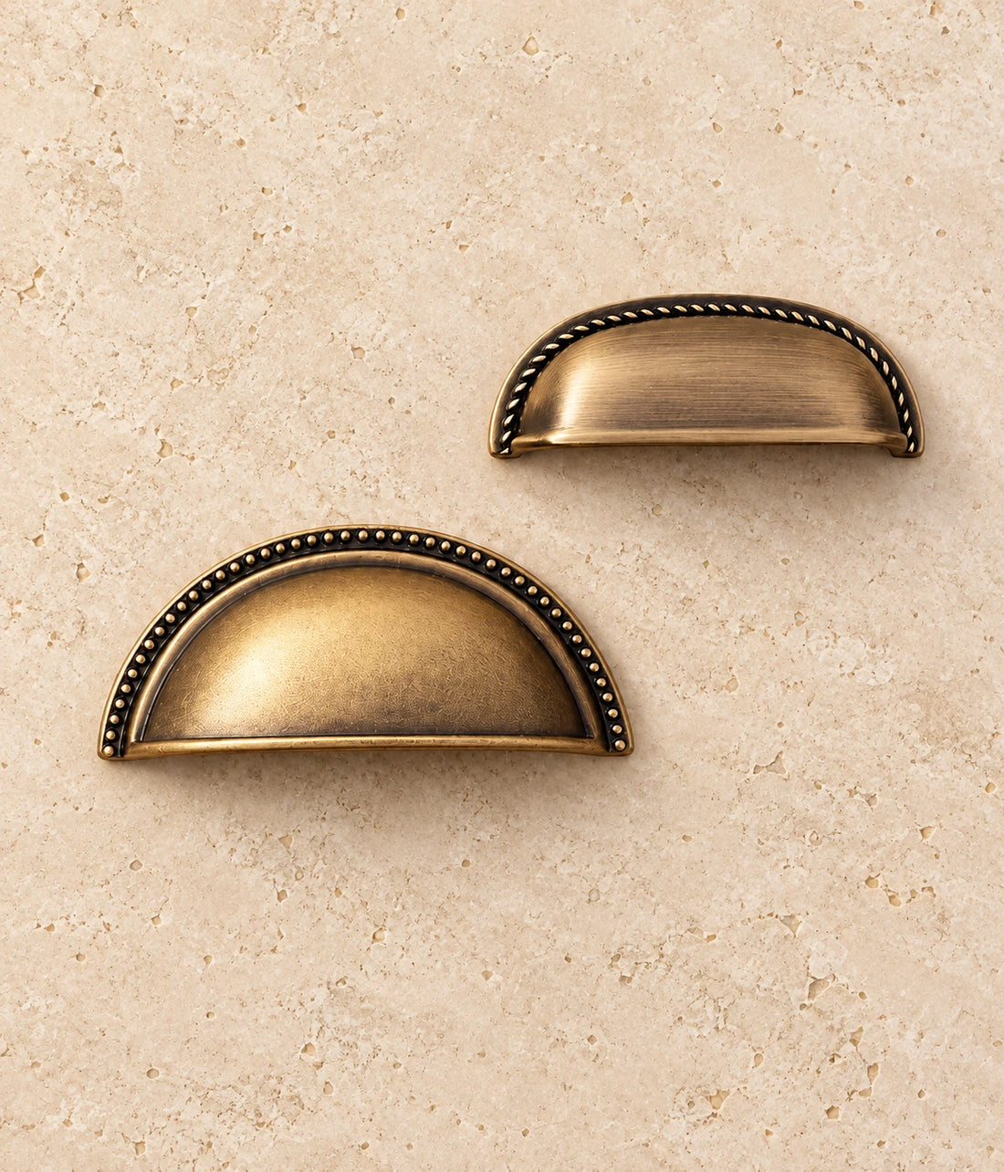 Antique Brass Rope-Edge & Deep Beaded Cup Pulls on warm limestone