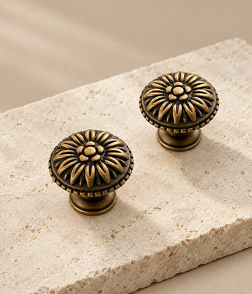 Two antique brass rosette cabinet knobs arranged on pale limestone