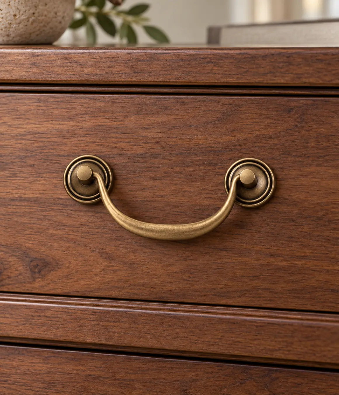 Antique brass round backplate bail pull on a walnut drawer